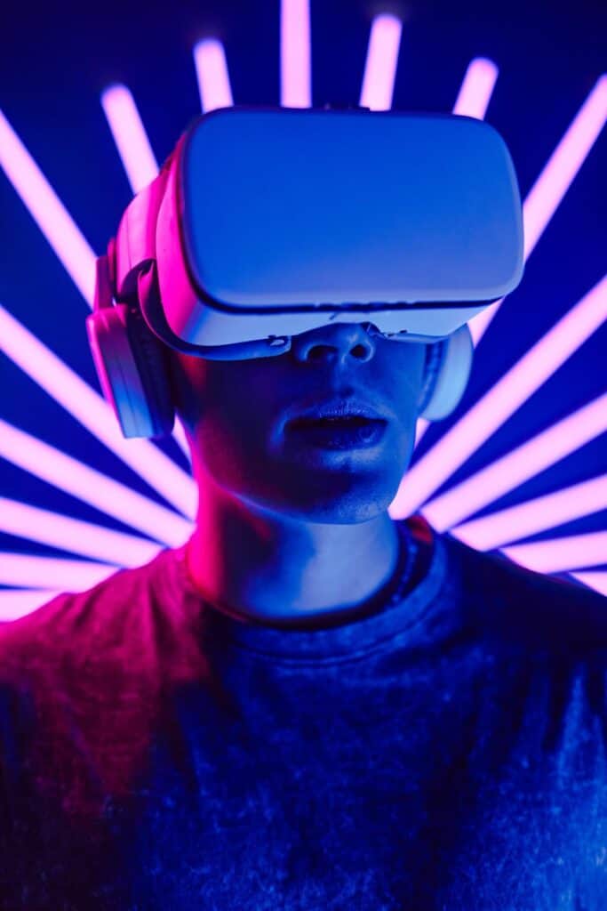 Virtual reality headset worn by a person in a dark environment with vibrant purple and pink neon lights radiating in the background, emphasizing immersive VR experiences.