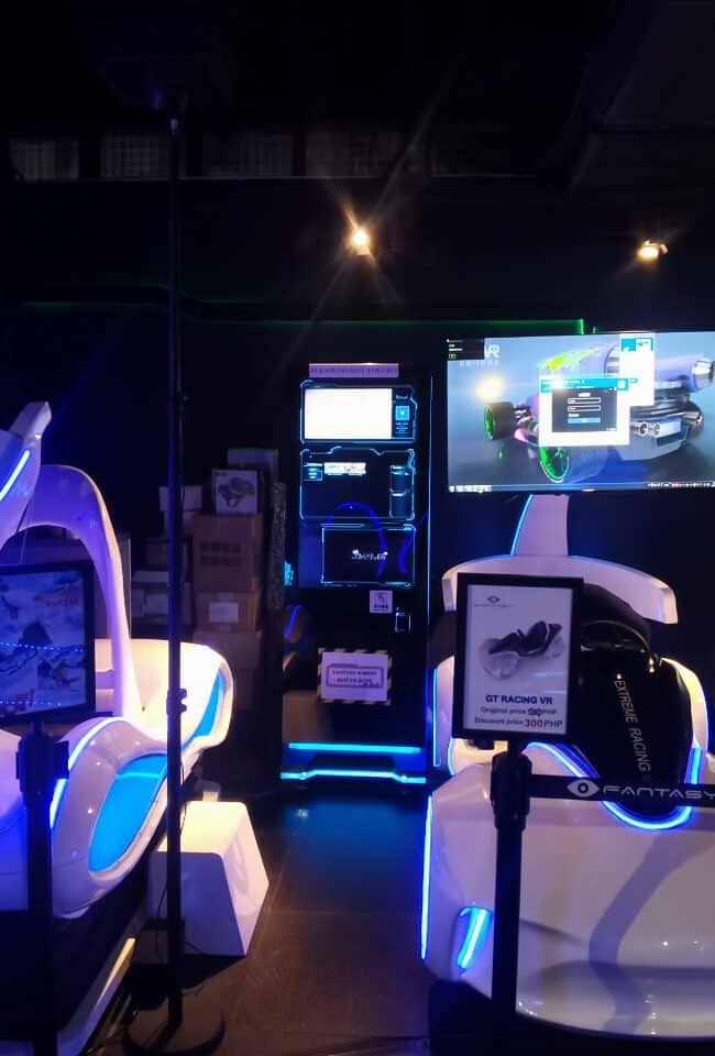 Futuristic virtual reality gaming setup with immersive racing simulators, large screens, and neon lighting for an exciting VR entertainment experience.