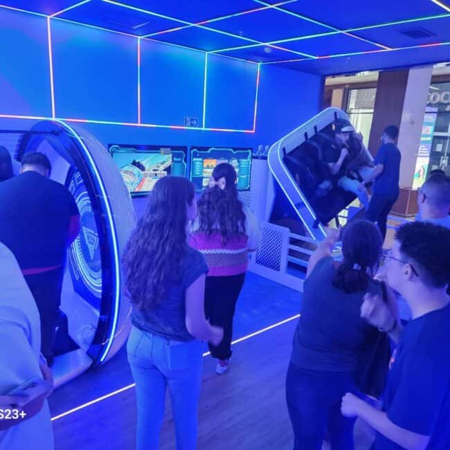 Futuristic virtual reality arcade with immersive gaming stations and vibrant blue neon lighting, attracting a diverse group of players engaging in virtual experiences.