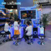 VR gaming kids experience - LEKEVR. Children playing virtual reality shooting game at tech expo, immersive VR arcade setup with multiple stations, kids having fun with interactive gaming including eye-catching neon lighting, branded LEKEVR signage.