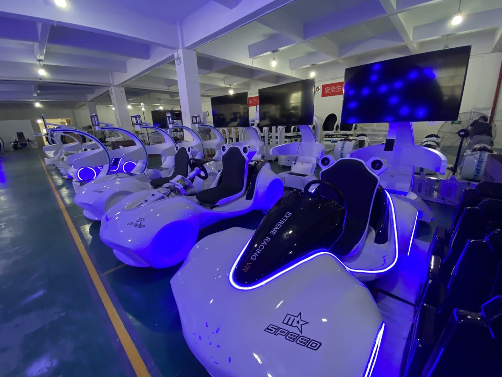Modern virtual reality ride station with sleek white pods and blue LED lighting, designed for immersive gaming experiences in an entertainment center.