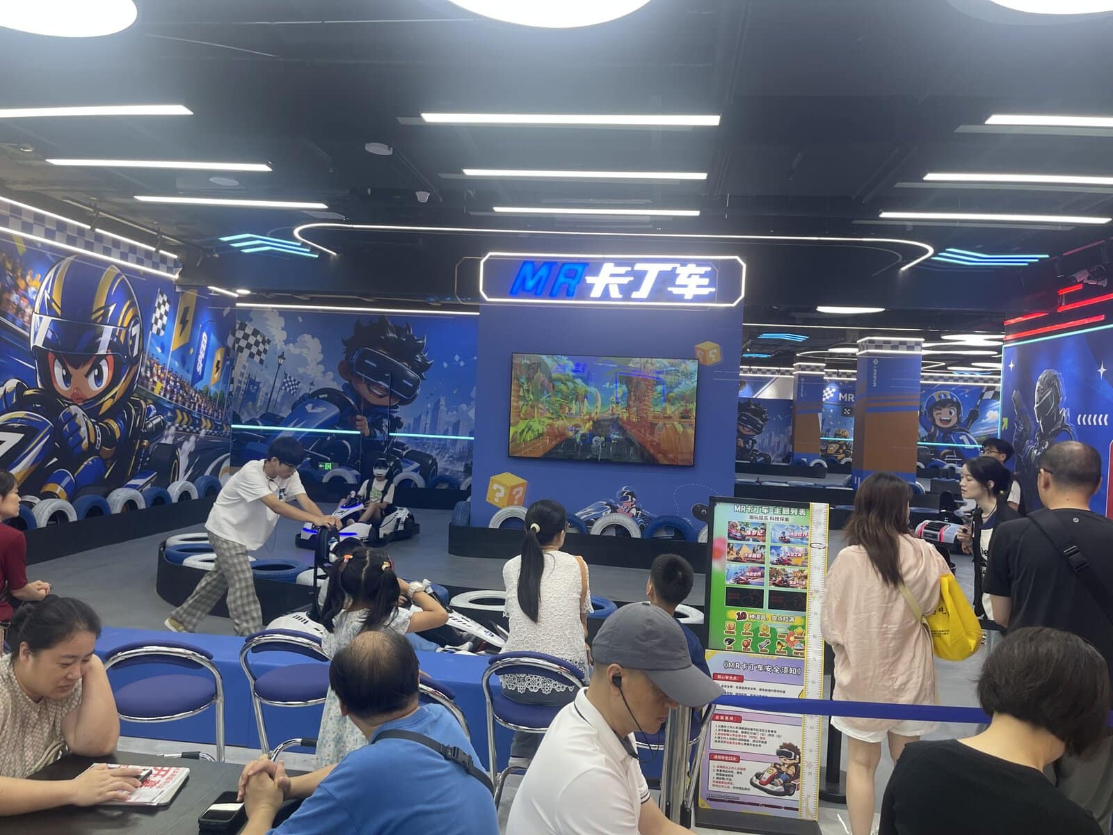 Virtual Reality Examples: Inside LEKE VR's New 1,000㎡ Flagship at Shanghai PRISMA Center 4 LEKE VR Shanghai store racing zone with guests using VR go kart simulator VR motorcycle racing kart and 360-degree double-player VR chair, crowd watching nearby